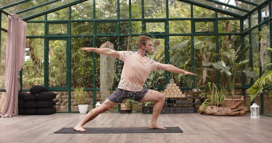 Man starting Warrior II pose sliding into Extended Side Angle in glass studio enhancing fitness. Balance, flexibility, mindfulness, wellness, natural, calming, harmony