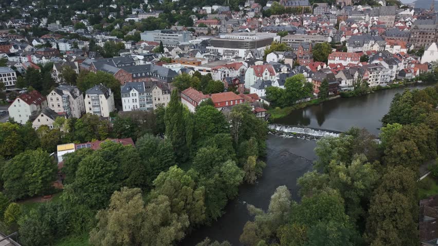Aerial view of a European town with a river, trees, and buildings.
