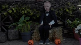 Child in a costume celebrates Halloween, holding a pumpkin basket on the street. Child grimaces at the camera. Concept of Halloween, holiday, and childhood. 4K slow-motion video - Powered by Shutterstock - Get 15% off with code: PIKWIZARD15