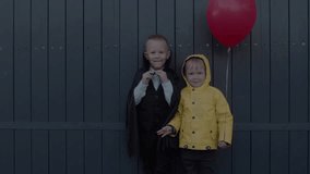 Children in costumes celebrate Halloween, holding a pumpkin basket on the street. Children make faces at the camera. Concept of Halloween, holiday, and childhood. 4K slow-motion video - Powered by Shutterstock - Get 15% off with code: PIKWIZARD15