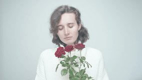 Thoughtful Gaze and Gentle Smile of a Woman with Curly Hair in a White Sweater as She Contemplates Red Roses in a Bright Indoor Setting - Powered by Shutterstock - Get 15% off with code: PIKWIZARD15