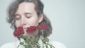 Direct Mysterious Gaze: Close-up of a Woman with Curly Hair Engaging with Red Roses, Transitioning from Thoughtful to Joyful Expressions in Soft Lighting - Powered by Shutterstock - Get 15% off with code: PIKWIZARD15