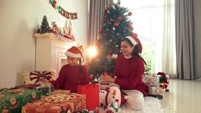 Cozy holiday morning in a bright living room as a parent and child in Santa hats open Christmas presents by a decorated tree and fireplace with stockings, garlands, and warm winter light. - Powered by Shutterstock - Get 15% off with code: PIKWIZARD15