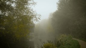 Misty morning covering calm river with narrow path along shore. Creeping mist wrapping ancient path forming mysterious feeling. Foggy dawn veiling still water beside trail bordered by autumn woods - Powered by Shutterstock - Get 15% off with code: PIKWIZARD15