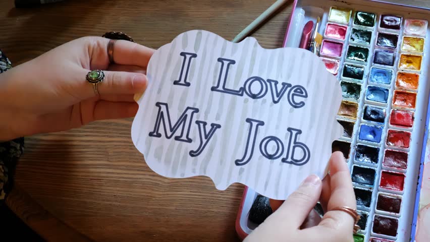 Young Woman Holds Up Watercolor Painted Card with the Words I Love My Job on Handmade Card in 4K Video Stock Footage