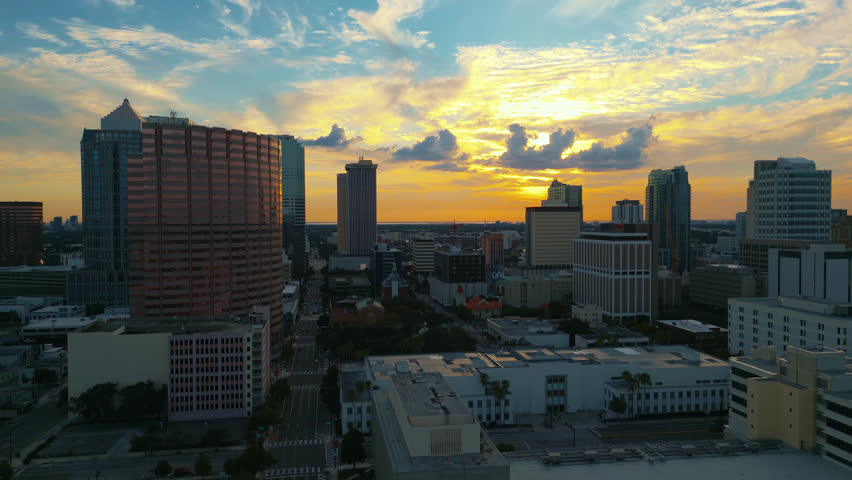 Tampa skyline as the day ends and sunset begins with golden light reflecting off of buildings, aerial flying forward.