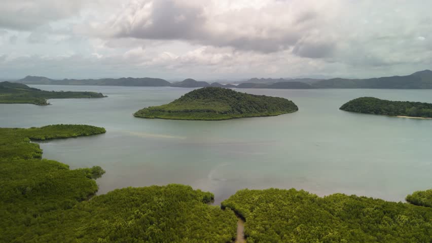 Drone footage showing a tropical island landscape with lush mangroves and calm ocean water near Koh Jum Island, Krabi, Thailand.
