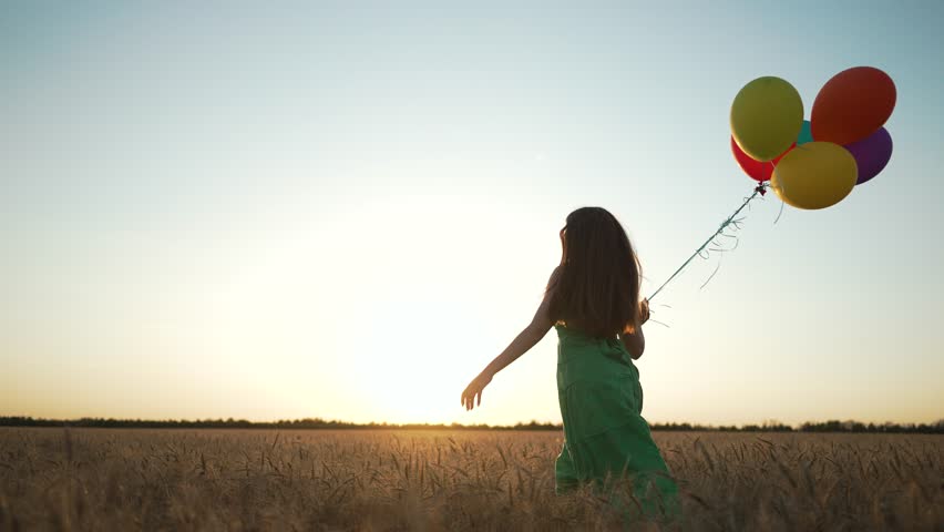 Woman in dress runs with balloon. woman with balloon runs through wheat field. Freedom and happiness concept. Woman running feeling free. Balloon adds playful touch. Woman run with balloon outdoors.