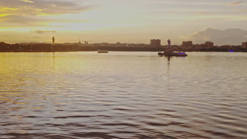 Hussain sagar lake with tourist boat, Gautama Buddha statue and ambedkar statue. sun set time, hand held shot, stable shot, 4k.