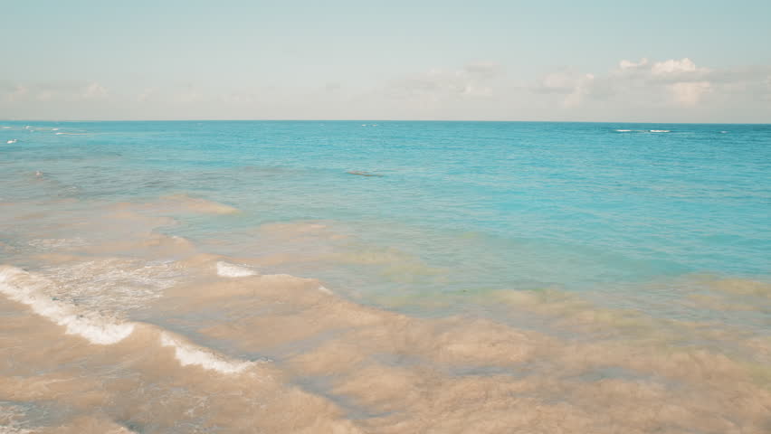 Turquoise ocean meets shore with dirty brown water swirling in the foreground in Mexico