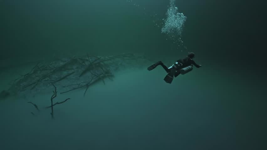 Scuba diver is suspended in the crystal-clear freshwater layer of Angelita Cenote, just above the famous hydrogen sulfide cloud.