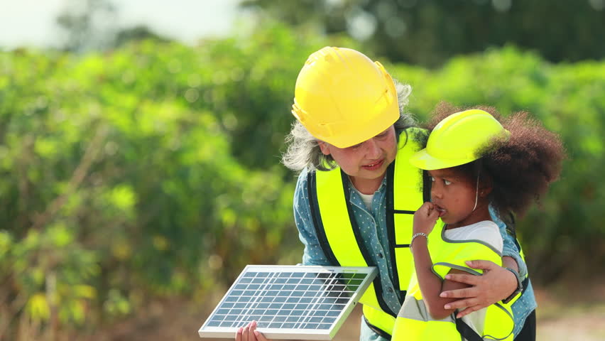 Engineer black girl Playing with Toy Wind Turbine and asian senior woman in Wind Farm. Windmill. environmental renewable clean energy. Wind power generation. Nature Outdoor activitie. solar panel
