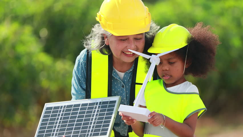 Engineer black girl Playing with Toy Wind Turbine and asian senior woman in Wind Farm. Windmill. environmental renewable clean energy. Wind power generation. Nature Outdoor activitie. solar panel
