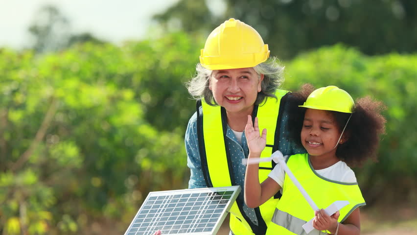 Engineer black girl Playing with Toy Wind Turbine and asian senior woman in Wind Farm. Windmill. environmental renewable clean energy. Wind power generation. Nature Outdoor activitie. solar panel
