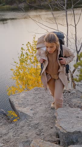 Front view of sporty blonde with backpack climbing up on canyon stones and grabbing man