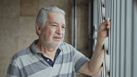 Elderly Man Gripping Metal Bars While Looking Outside And Crying With Distressed Expression - Powered by Shutterstock - Get 15% off with code: PIKWIZARD15