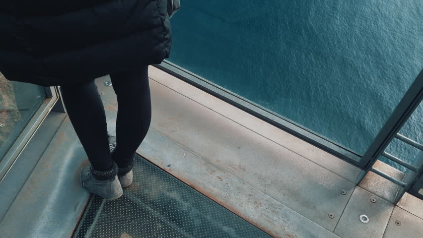 woman looking at the ocean and landscape from the Cabo Girao skywalk in Madeira, Portugal