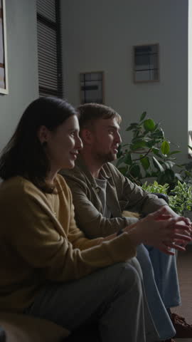 Vertical side view shot of happy young couple speaking with smiles and embracintg in therapy session woman nodding in agreement