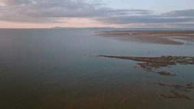 Two Lone Fishermen Standing On The Tide Line Of The Irish Sea At Low Tide At Sunset. Fleetwood, Lancashire, UK. - Powered by Shutterstock - Get 15% off with code: PIKWIZARD15