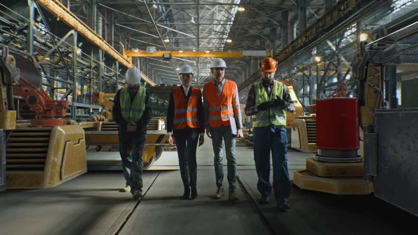 Team of Men and Women Wearing Protective Vests and Helmets Walks Around and Discusses Large Industrial Facility Surrounded by Glowing Blue Digital Grid. Concept Internet of Things, Augmented Reality.