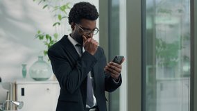 African American businessman looking serious at smartphone reading bad news texting using mobile phone business man sad male professional in office worried about message digital communication stress - Powered by Shutterstock - Get 15% off with code: PIKWIZARD15