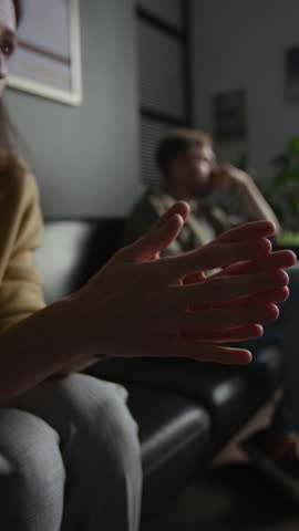 Vertical closeup shot of young woman speaking emotionally in therapy session for couples with focus on hands gesturing and covering face
