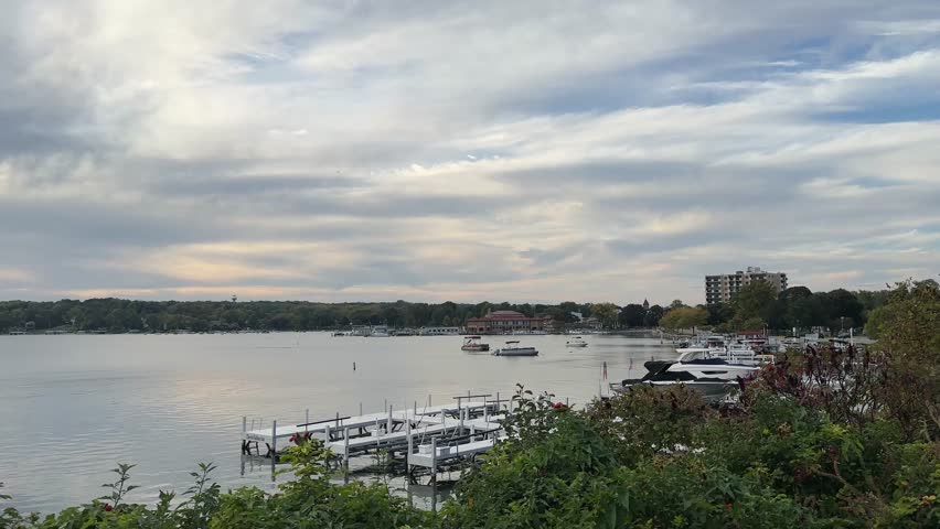 Boats And Docks On Calm Waters Of Geneva Lake On Cloudy Day In Wisconsin, USA. Lakeside Town In Distance. wide shot