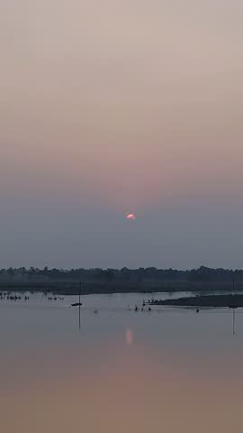 Rural sunset scene with farmland and orange sky. Sunset