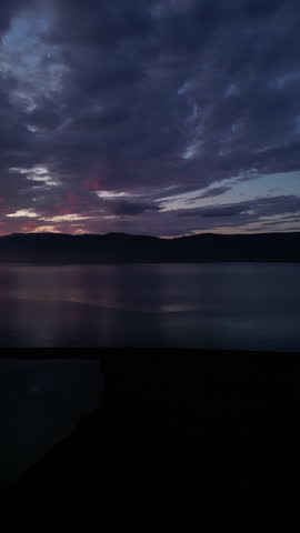 Aerial pan to setting sun illuminating clouds glowing red orange, Gasir Akureyri Iceland
