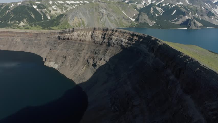 Aerial view of Crater Lake National Park, Oregon, USA, from the rim near Watchman Peak. Sheer volcanic cliffs drop to deep blue waters surrounded by rugged mountain scenery and lush forest slopes.