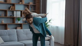 Happy Caucasian family playing at home father holding daughter piggyback dad carrying on back little girl kid child pretending airplane flying funny play having fun fooling together childcare game - Powered by Shutterstock - Get 15% off with code: PIKWIZARD15