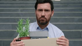 Upset unemployed fired Caucasian middle aged business man lost job looking at camera sad holding dismissal box sitting stairs near office building dismiss businessman male unemployment finance crisis - Powered by Shutterstock - Get 15% off with code: PIKWIZARD15