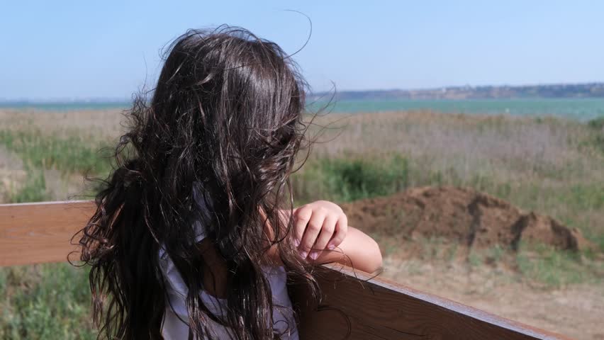 A beautiful and confident young girl is enjoying a sunny, windy day