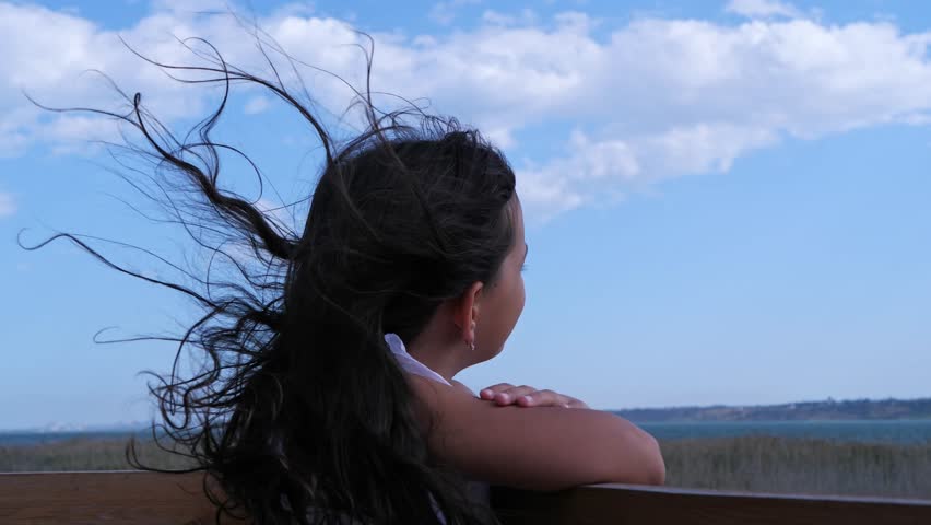 A thoughtful young girl with her hair blowing in the wind