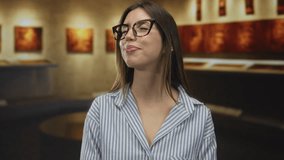 Woman wearing glasses and striped shirt closes eyes in museum gallery while viewing abstract painting; serenity reflection admiration. - Powered by Shutterstock - Get 15% off with code: PIKWIZARD15