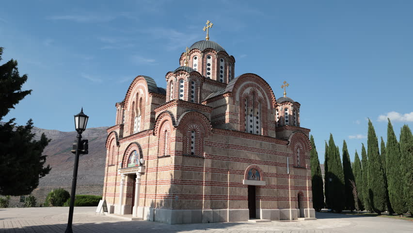 Church of Virgin Mary, central building of Hercegovacka Gracanica monastery, is located on hill among mountains. Tall cypresses, blue sky, peaceful and blissful atmosphere of Orthodox monastery