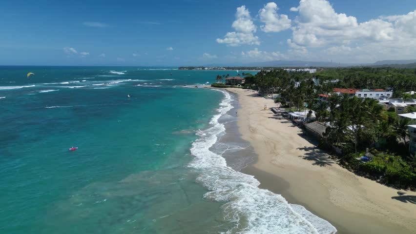 High drone view of kite boarders along the Cabarete shore — motion, colour, and tropical scenery. Best for surf culture and destination footage