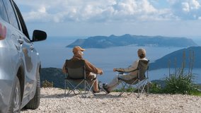 Tourists in camping chairs take a break from a road trip. Retired travelers enjoying at scenic mountain overlook, sitting in camping chairs and taking in sweeping coastal with parked vehicle nearby - Powered by Shutterstock - Get 15% off with code: PIKWIZARD15