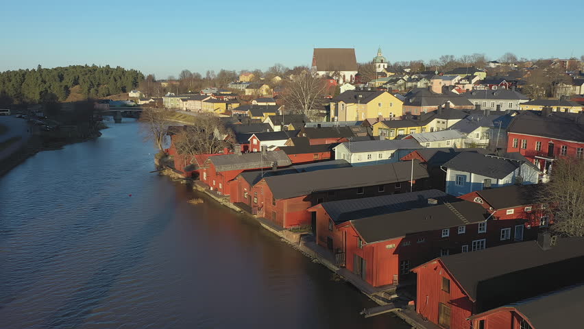 Porvoo.Finland-December 12.2020: Calm drone shot of the Northern riverside wooden houses in Porvoo Finland with green forest in the background on a sunny day in late autumn