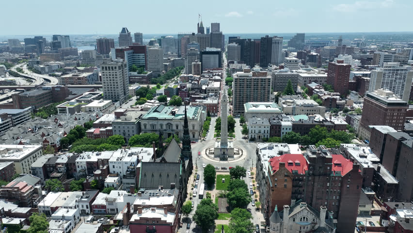 Morning sun shines on the beautiful monument and historic building architecture in the heart of the Mount Vernon neighborhood of Baltimore, Maryland, USA.