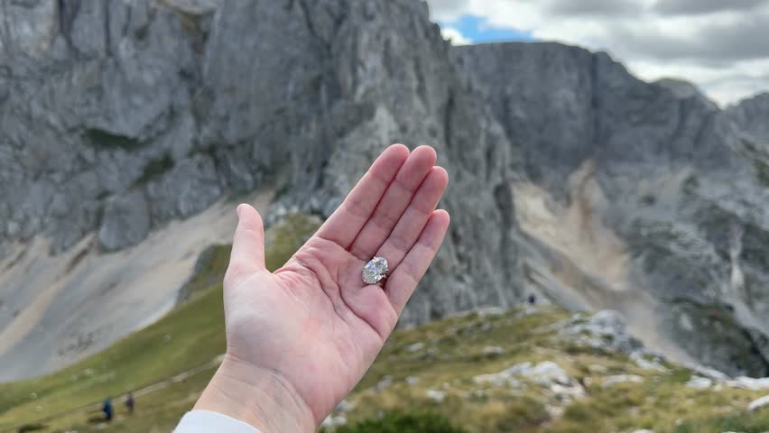 Landscape video capturing a sparkling oval diamond engagement ring in natural Montenegrin light with stunning mountain scenery in the background.