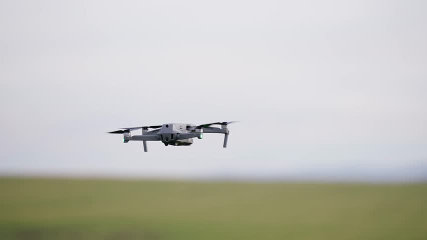 Grey drone quadcopter with digital camera and sensors flying in slow motion