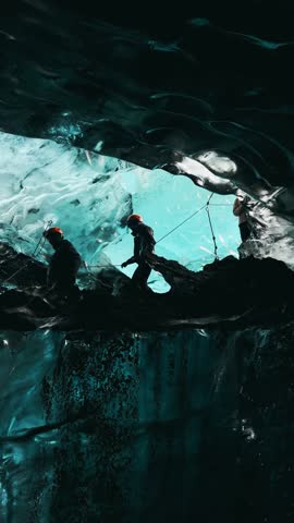 People exploring an amazing glacial cave in Iceland, vertical orientation