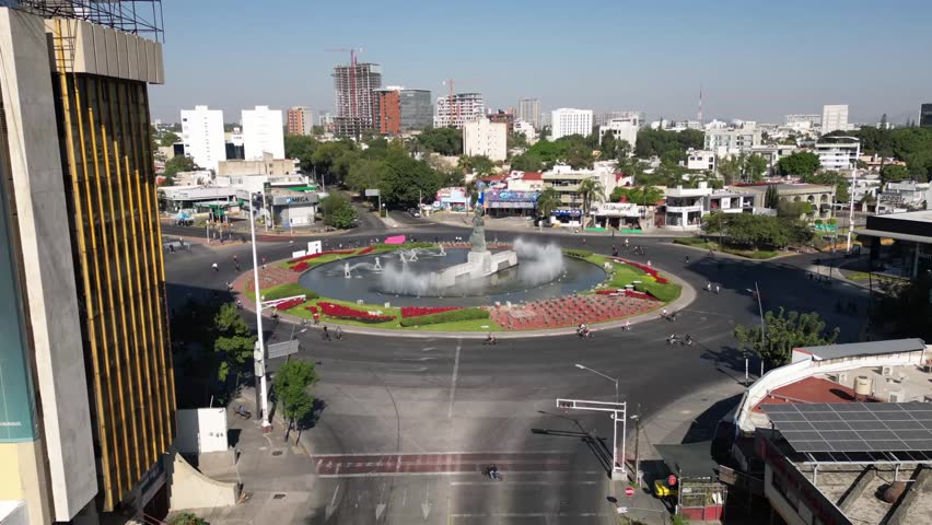 Aerial timelapse showing La Minerva fountain with urban activity, cyclists, and traffic in Guadalajara, Mexico
