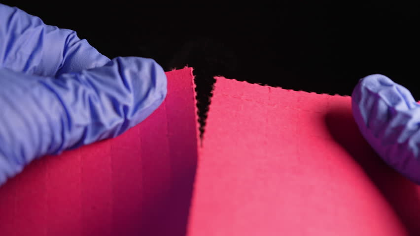 Hands of the drug dealer in gloves break or tear the LSD strip blotters with dry drops of Lysergic acid drug lucy or Ellis D. Hallucinogenic drug for sale in clubs, parties and street.