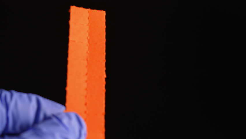 Hands of the drug dealer in gloves break or tear the LSD strip blotters with dry drops of Lysergic acid drug lucy or Ellis D. Hallucinogenic drug for sale in clubs, parties and street.