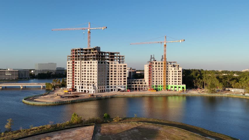 Ongoing construction of two buildings between green area in front of beautiful lake