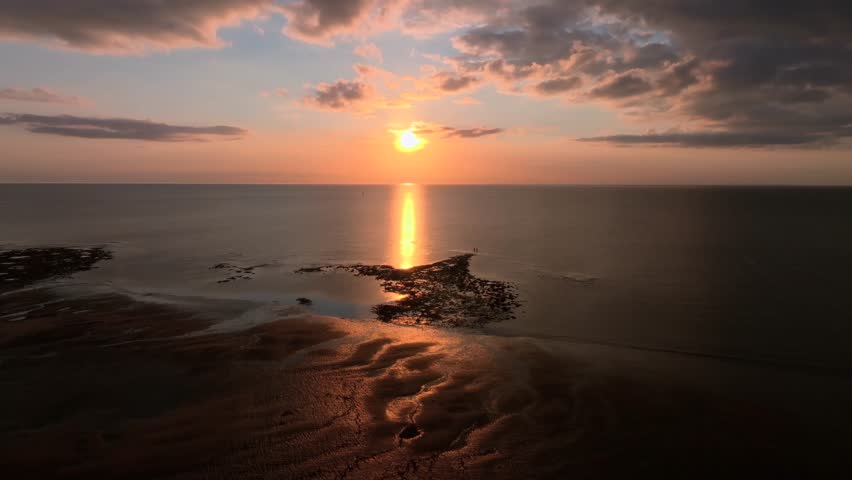 Two Lone Figures Standing On The Tide Line Near Calm Sea At Sunset. Golden Hour. Fleetwood, Lancashire, UK.
