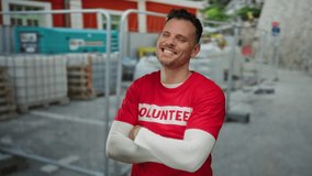 Young man with volunteer shirt stands confidently at outdoor construction site showcasing community involvement. - Powered by Shutterstock - Get 15% off with code: PIKWIZARD15