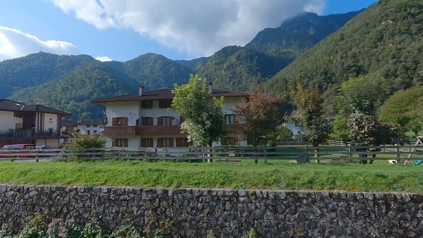 View of alpine houses and greenery in Pieve di Ledro near Ledro Lake in Trentino Italy surrounded by mountains under a blue sky